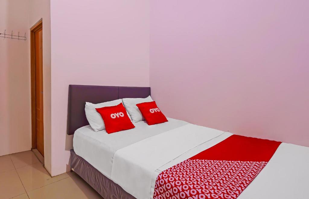 a bedroom with a bed with two red pillows at Super OYO 92664 Cemara Koja Residence Syariah in Jakarta