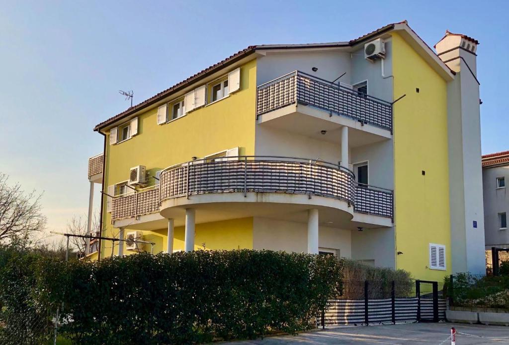 a yellow and white building with a balcony at Goldfinch Estate in Banjole