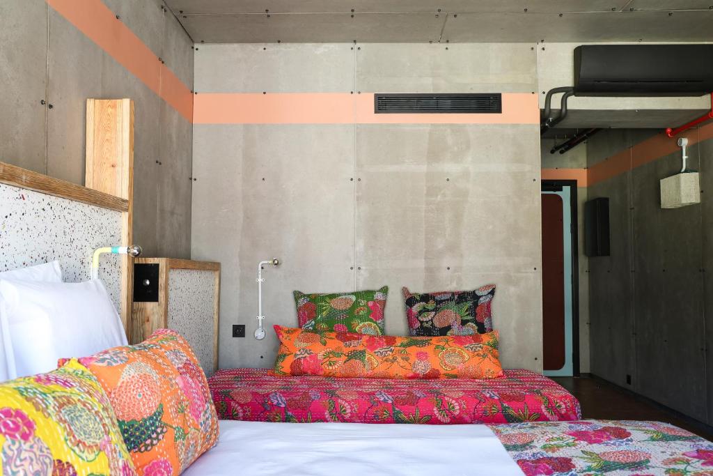 A colorful bedroom with a double bed, daybed and wall-mounted fold-down bunk.
