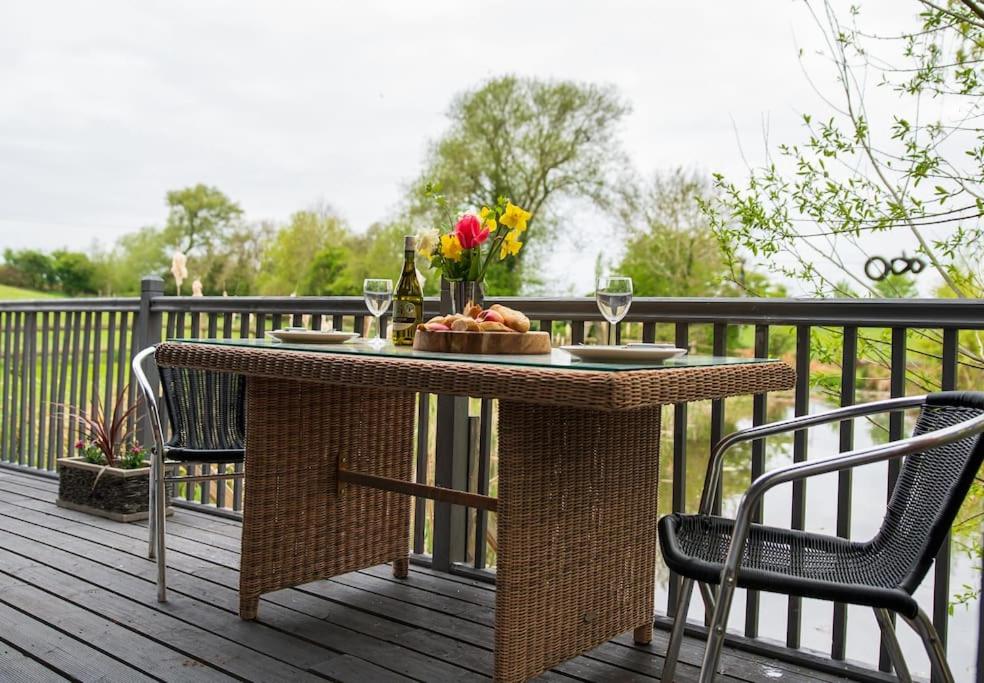 una mesa con un plato de comida y dos sillas en una terraza en Lily pad Lodge en Rous Lench