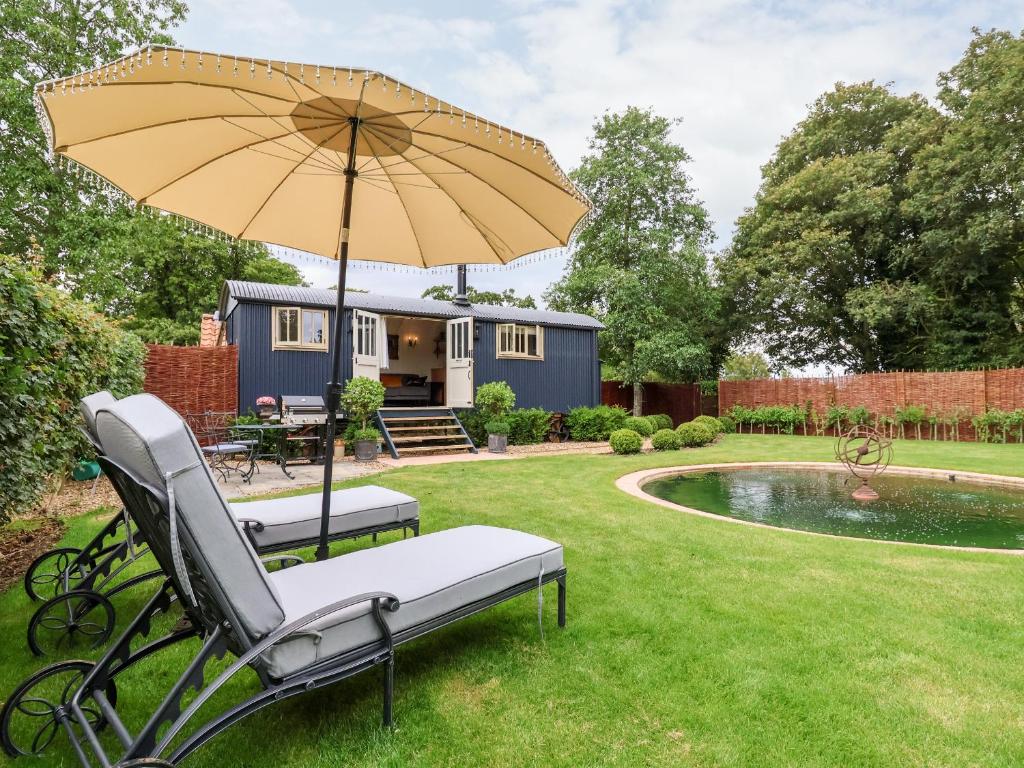 a garden with a bench and an umbrella and a house at Utopia in Harleston