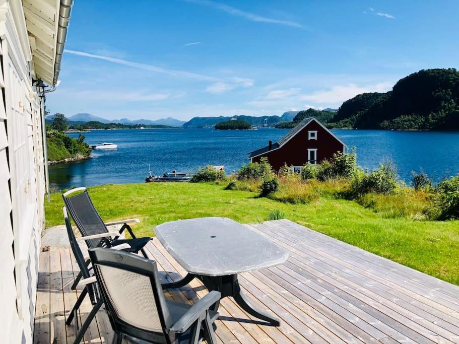 een tafel en stoelen op een terras met uitzicht op een meer bij Waterfront Cottage (Fishing Opportunities!) in Ålesund