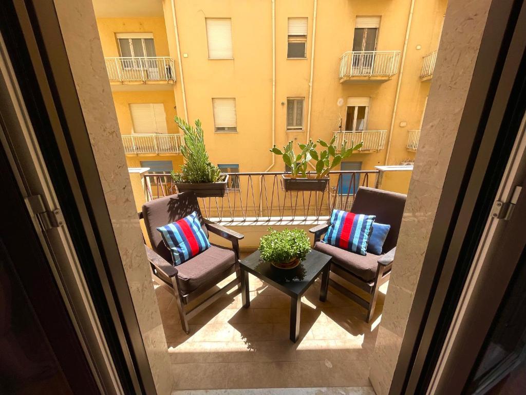 balkon z 2 krzesłami i stołem oraz budynek w obiekcie Golden House - Trilocale nel Cuore di Agrigento w mieście Agrigento
