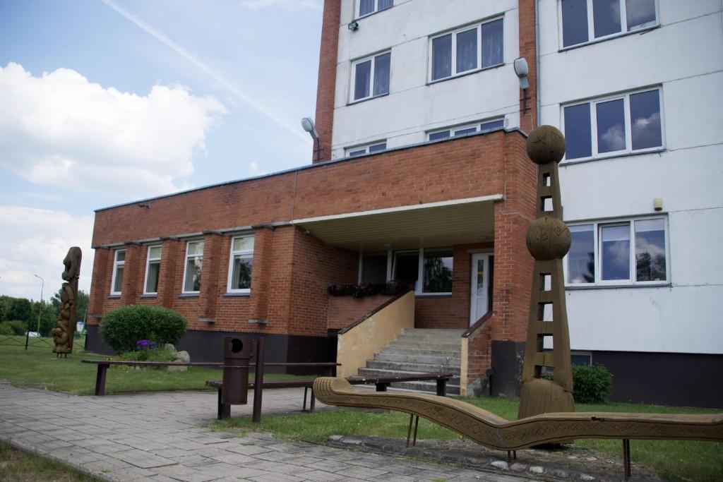 un edificio con una panchina di fronte a un edificio di VESK Veisiejai a Veisiejai