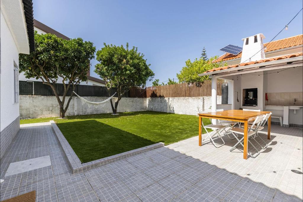 ein Hinterhof mit einem Holztisch und einem Rasen in der Unterkunft Lovely Beach House in Aroeira by LovelyStay in Aroeira