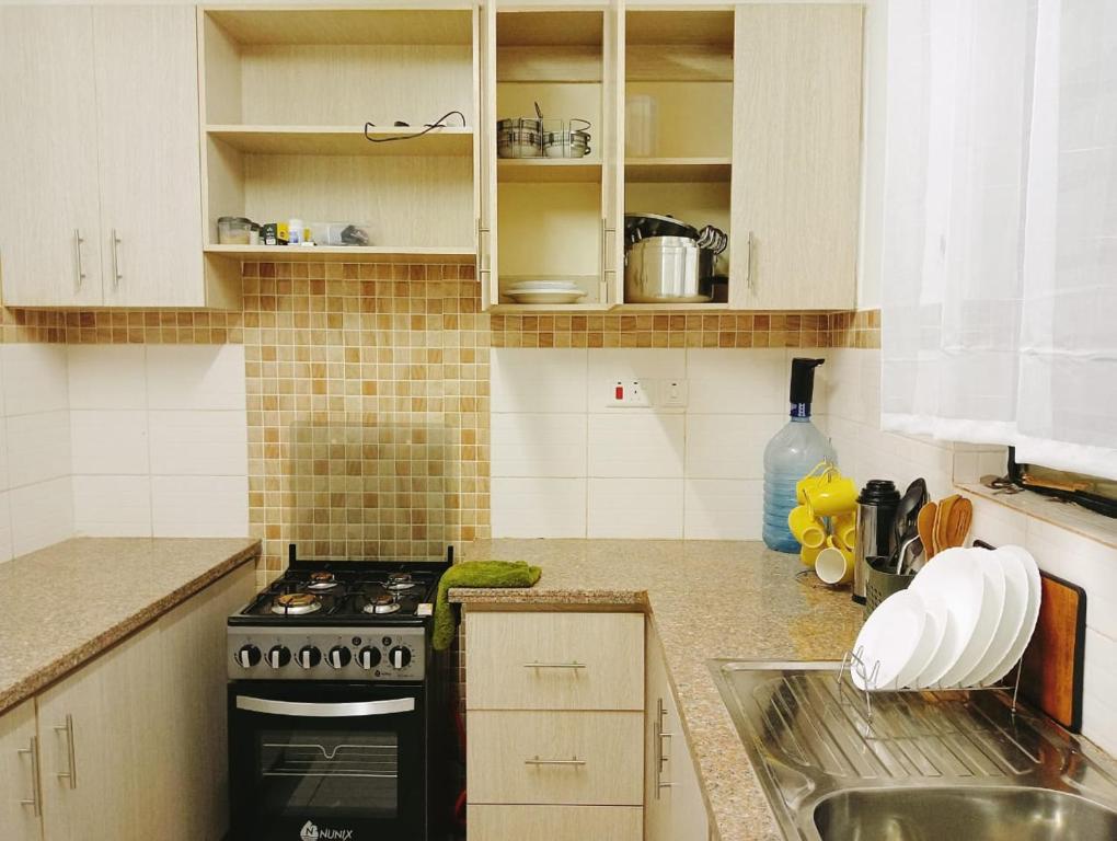 een keuken met een fornuis en een wastafel bij Three Bedroom Thika Road in Nairobi