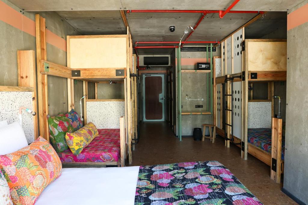 A wide view down a compact dormitory lined with bunks and a double bed.