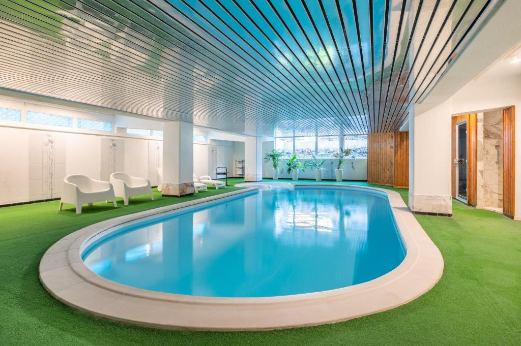 a large swimming pool in a room with chairs and tables at Grand Hôtel Des Templiers in Reims