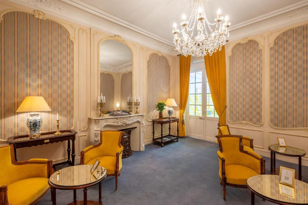 a living room with yellow chairs and a chandelier at Grand Hôtel Des Templiers in Reims