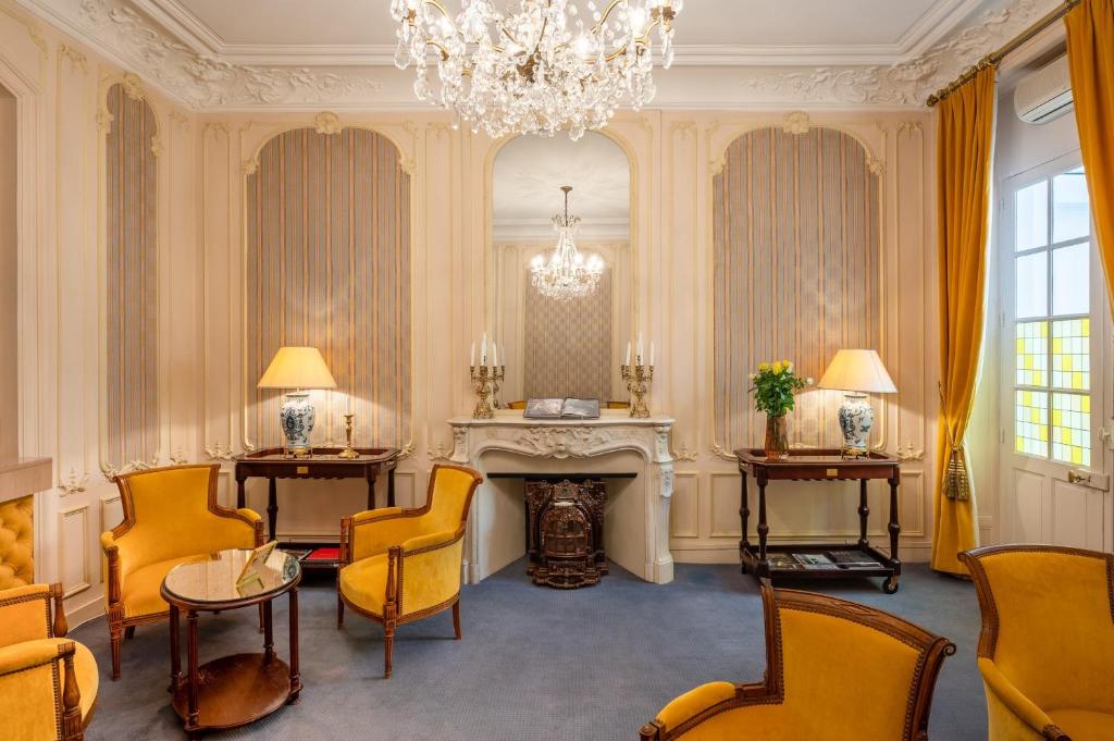 a living room with yellow chairs and a chandelier at Grand Hôtel Des Templiers in Reims