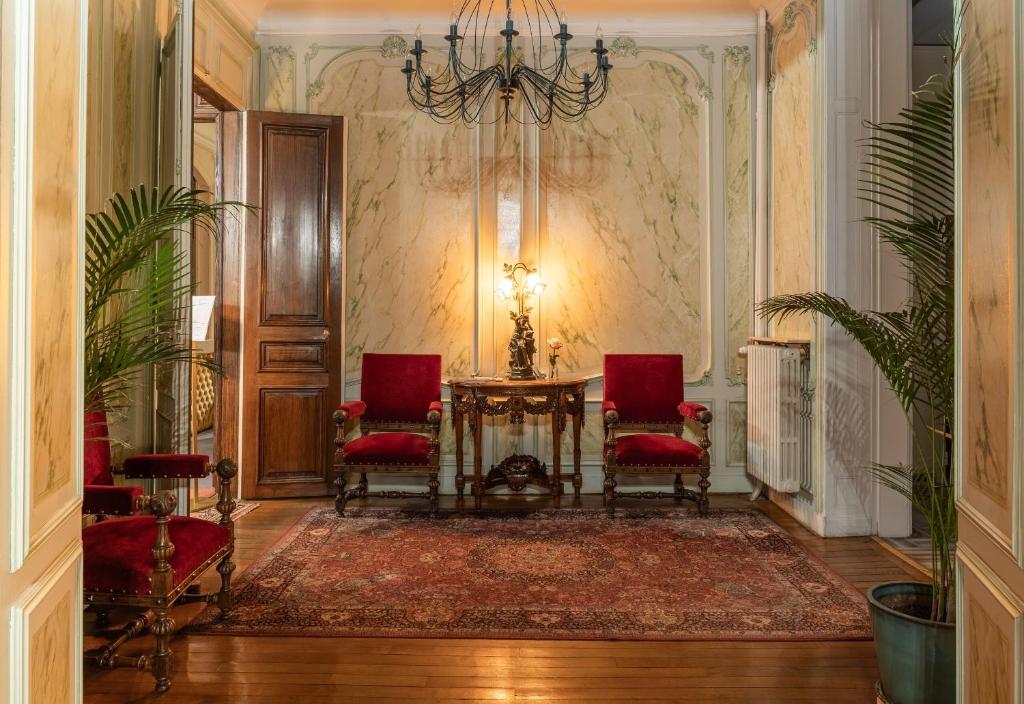 a hallway with a table and chairs and a chandelier at Grand Hôtel Des Templiers in Reims