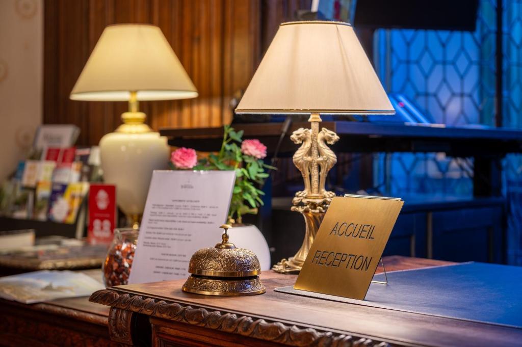 a table with a lamp and a sign on it at Grand Hôtel Des Templiers in Reims