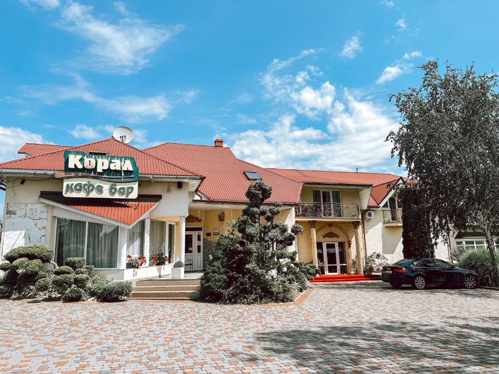 a building with a car parked in front of it at Koral Hotel in Verkhniy Koropets
