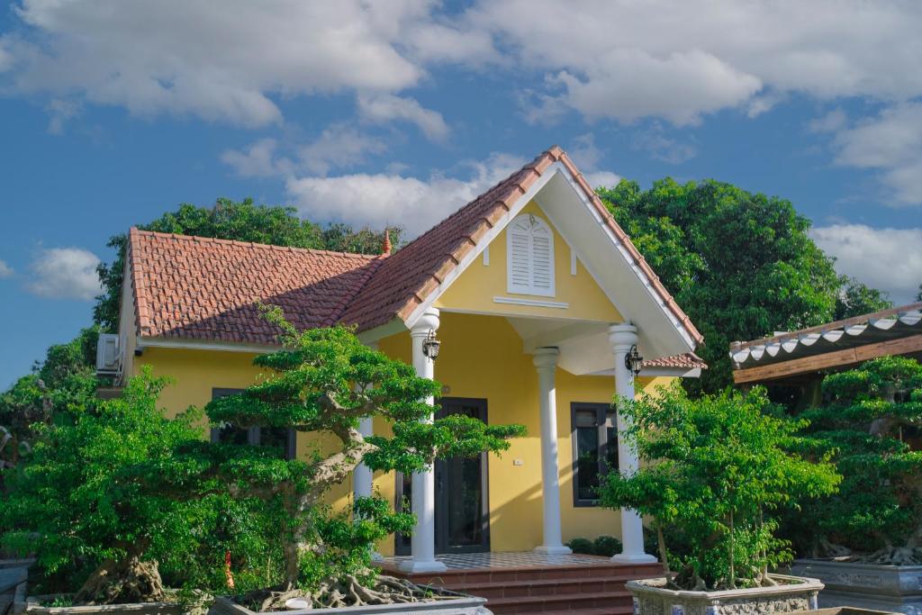 uma casa amarela com um telhado vermelho em Dong Giao Bungalows em Tam Ðiệp