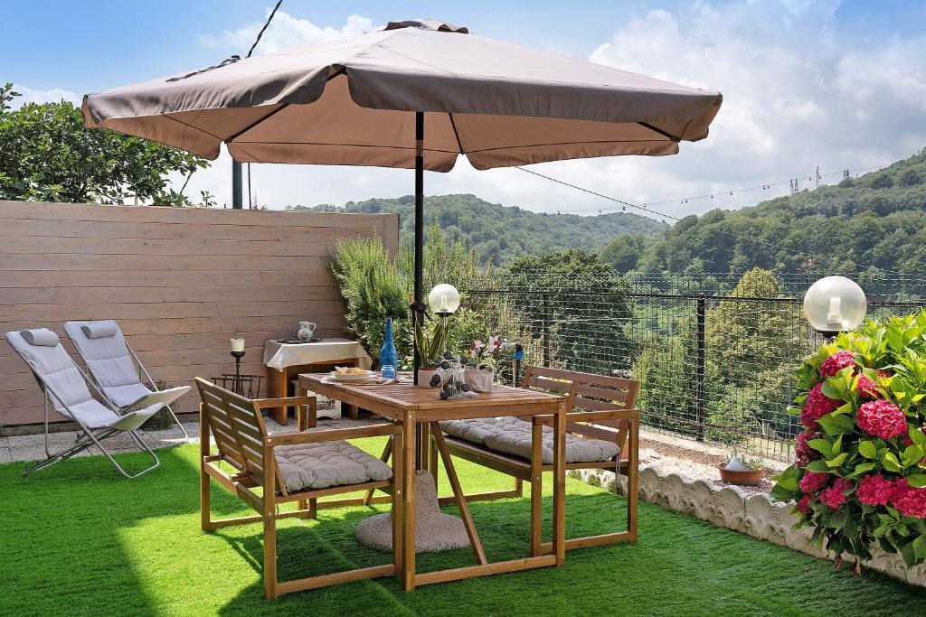 una mesa de madera con una sombrilla en el jardín en La Casa di Giosy, en Cairo Montenotte