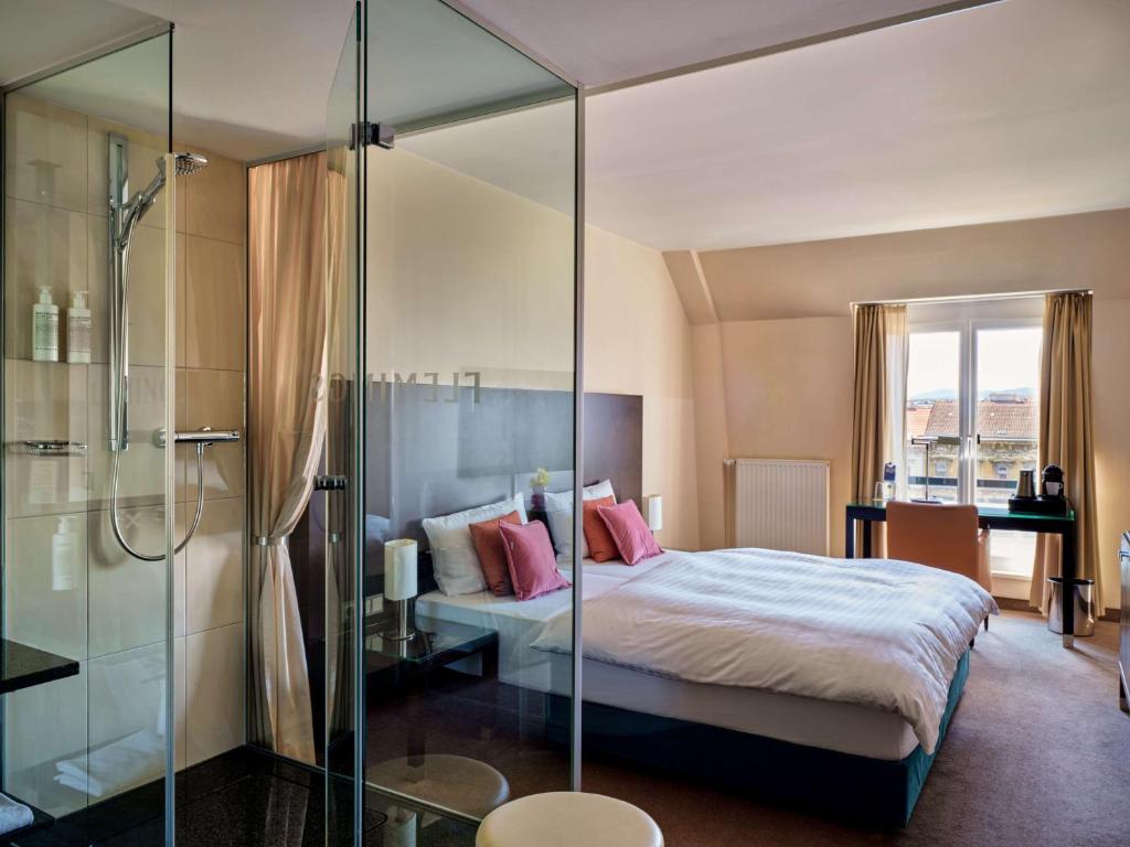 a bedroom with a bed and a glass shower at Flemings Hotel Wien-Stadthalle in Vienna