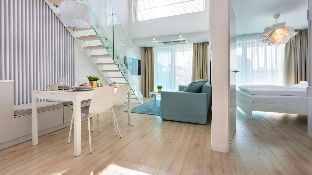 a living room with a white table and a staircase at VacationClub - WHITEblue Apartament 58 in Kołobrzeg
