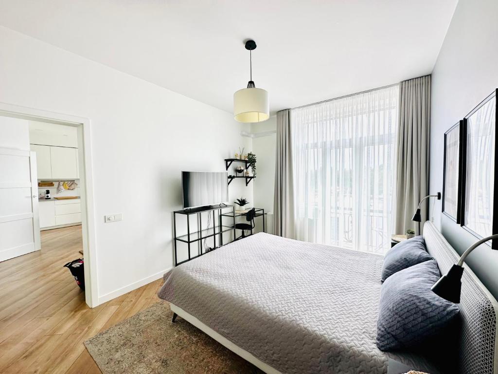Dormitorio blanco con cama y ventana grande en Butas pačiame Šiaulių miesto centre en Šiauliai