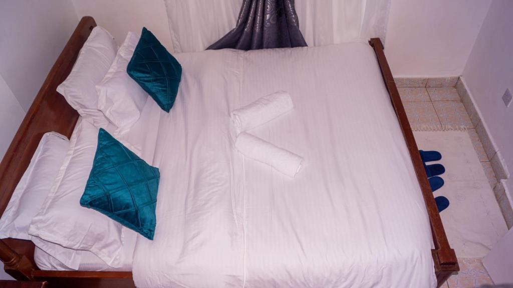 un letto bianco con due cuscini blu sopra di One Bed Garden Estate Nairobi a Nairobi