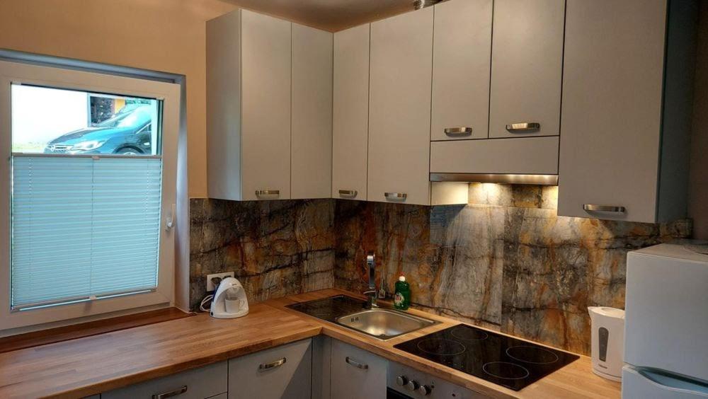 a kitchen with white cabinets and a sink and a window at Domki Całoroczne Południowy Stok in Gródek Nad Dunajcem