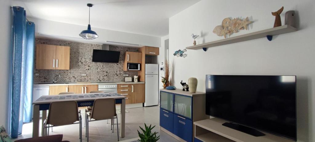 a kitchen with a tv and a table with chairs at Mar Salada in L'Ametlla de Mar