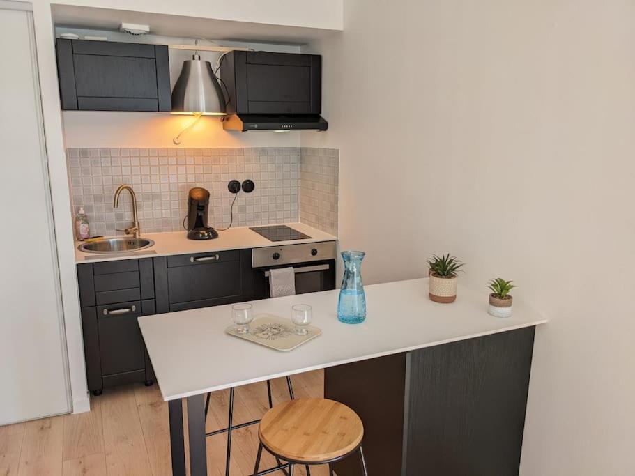 kuchnia z białym blatem i wyspą kuchenną w obiekcie Beau studio à deux pas de la gare - Kerlaouen w mieście Saint-Brieuc