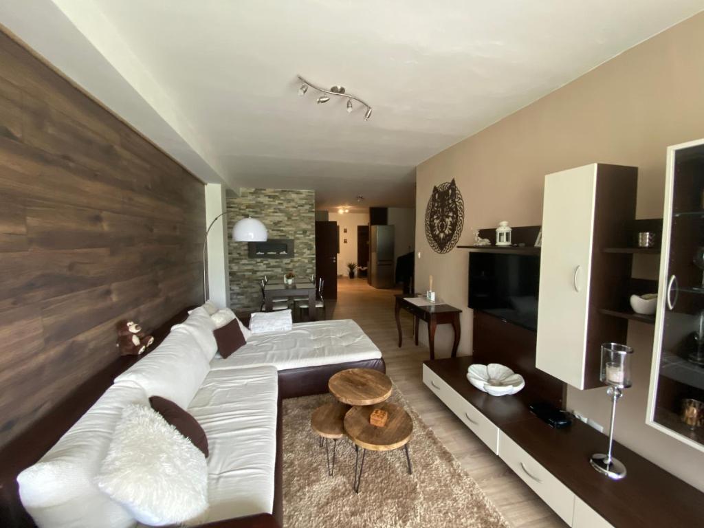 a living room with a white couch and a television at Apartmán s nádherným výhľadom na Tatry in Veľký Slavkov