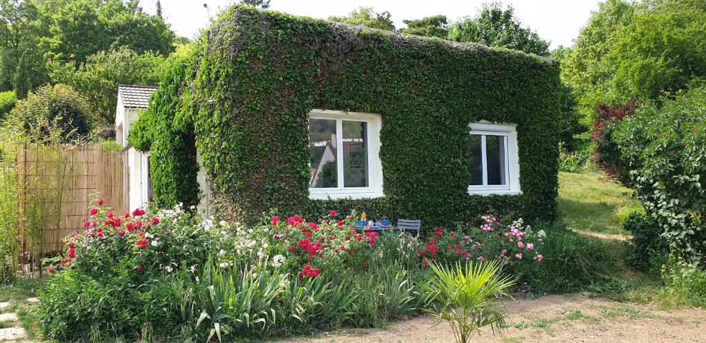 a house covered in ivy with flowers in a garden at Détente champêtre, maisonnette rénovée en 2023 
