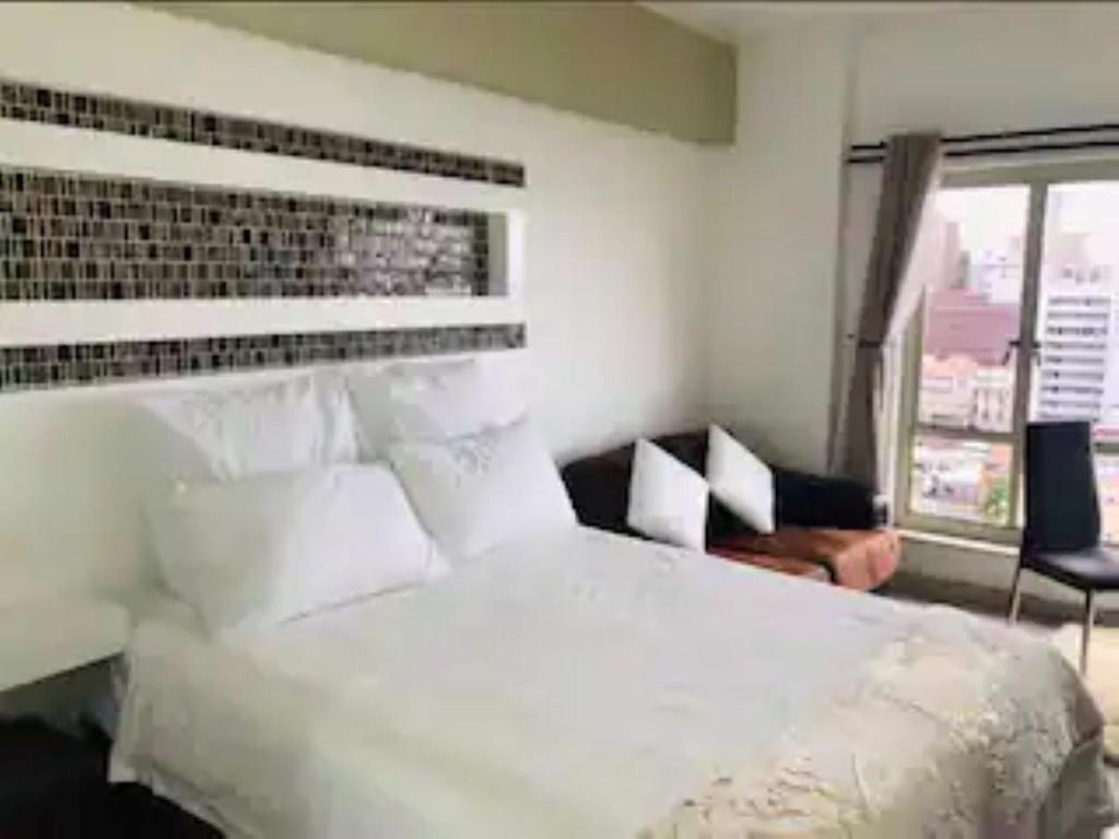 a bedroom with a large white bed and a window at Elegant Durban Harbor View Bnb in Durban