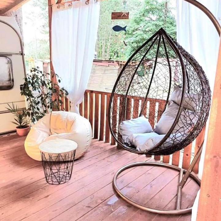 a porch with a swing and a chair on a deck at Каравана Summer time in Chernomorets