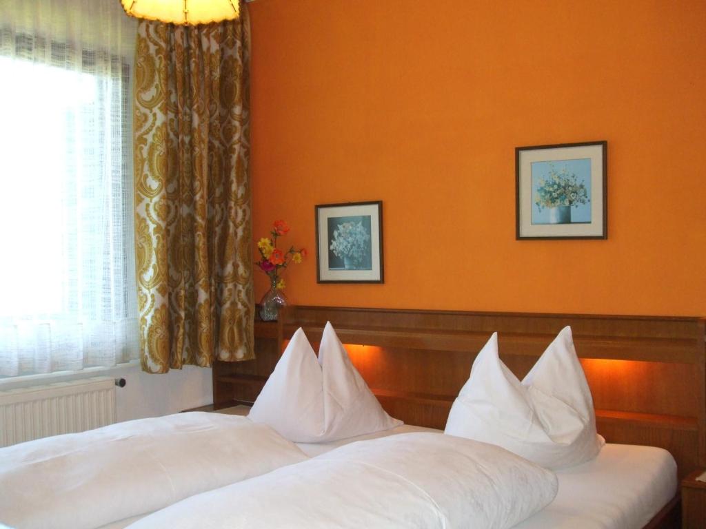 2 łóżka w pokoju hotelowym z pomarańczowymi ścianami w obiekcie Pension Brönimann w mieście Ossiach