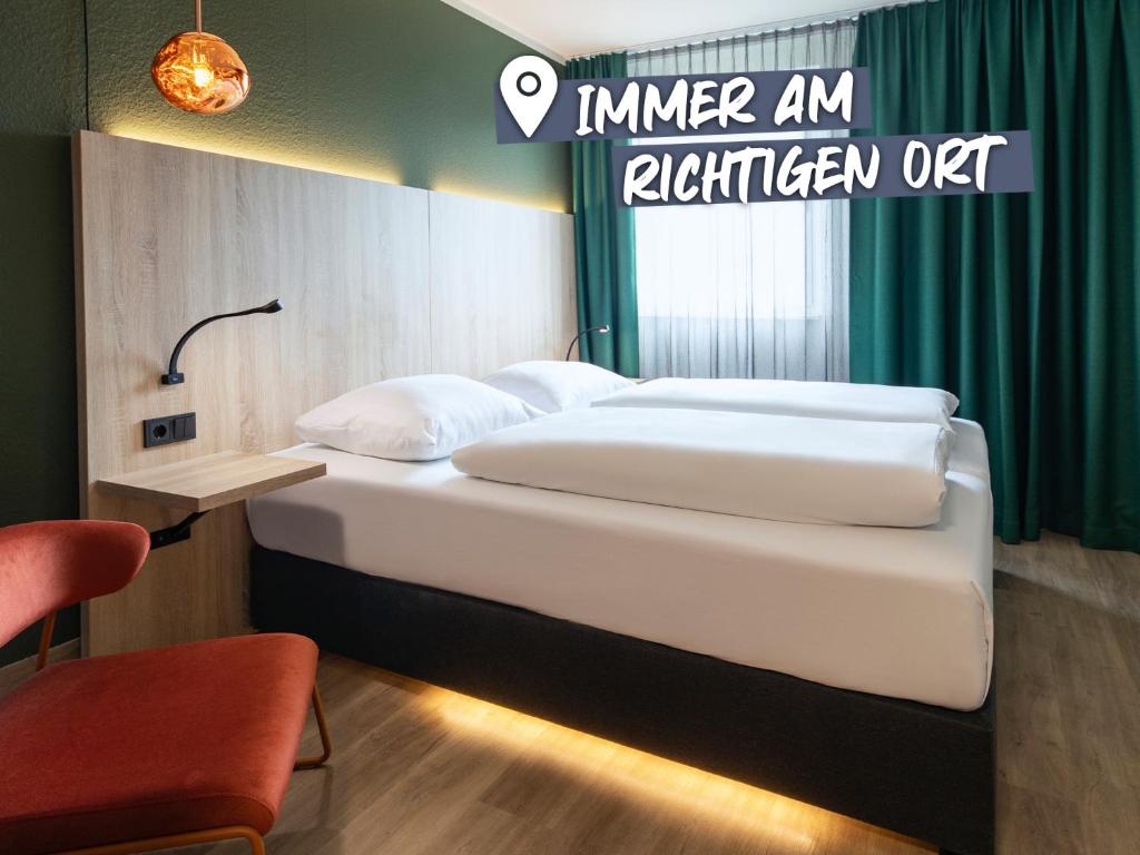 ein Bett in einem Hotelzimmer mit einem Schild, das eine Küche im Innenbereich ablegt in der Unterkunft ACHAT Hotel Monheim am Rhein in Monheim