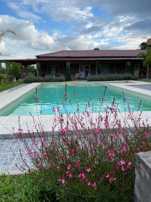 een huis met een zwembad met roze bloemen bij Casa Quinta Bella Vista in El Encón