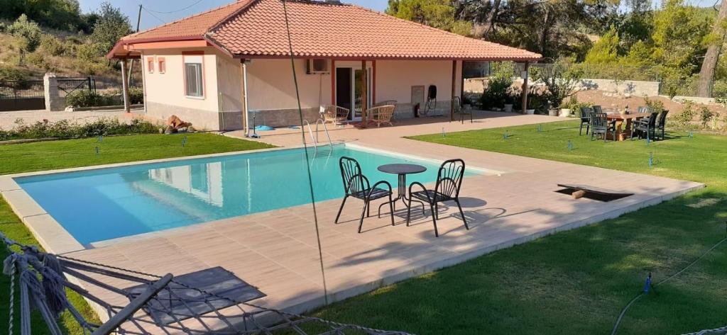 a swimming pool with a table and chairs next to a house at Villa Olymposzaray in Kumluca