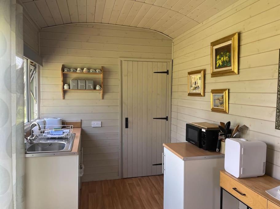 una pequeña cocina con fregadero y puerta en Lakeside Shepard's Hut 'Sanderling', en Bishampton