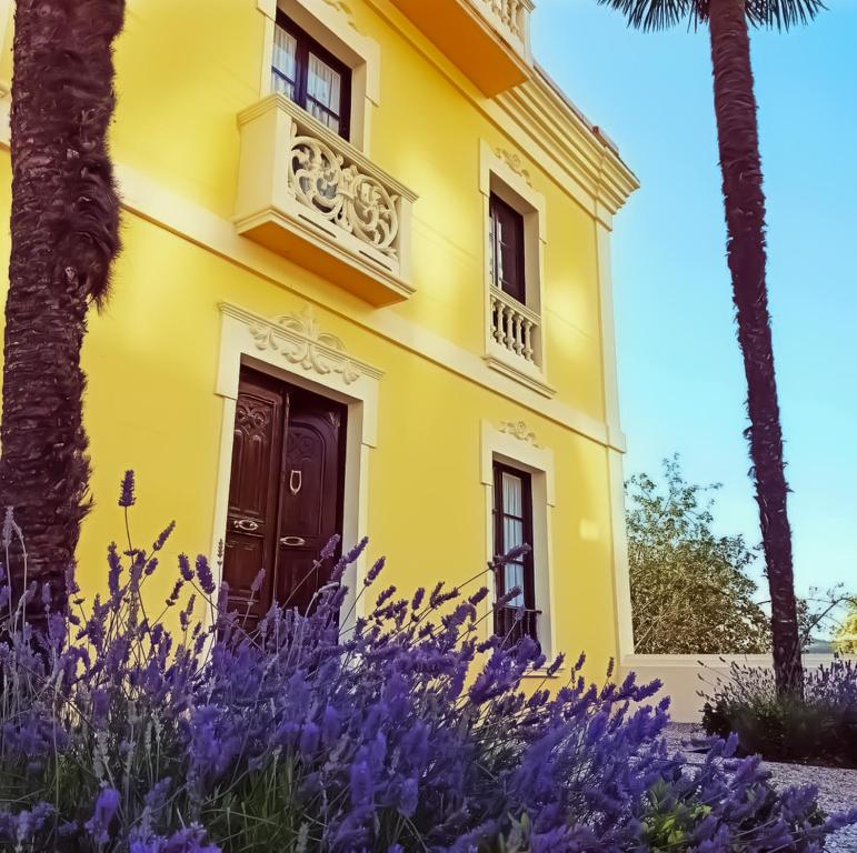 una casa amarilla con flores púrpuras delante de ella en Santa Emilia, en Mondoñedo