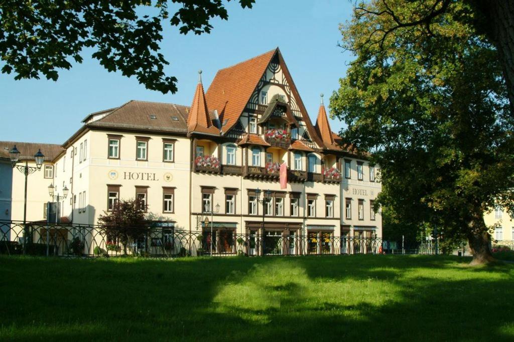 ein großes weißes Gebäude mit einem Baum davor in der Unterkunft Hotel Sächsischer Hof in Meiningen