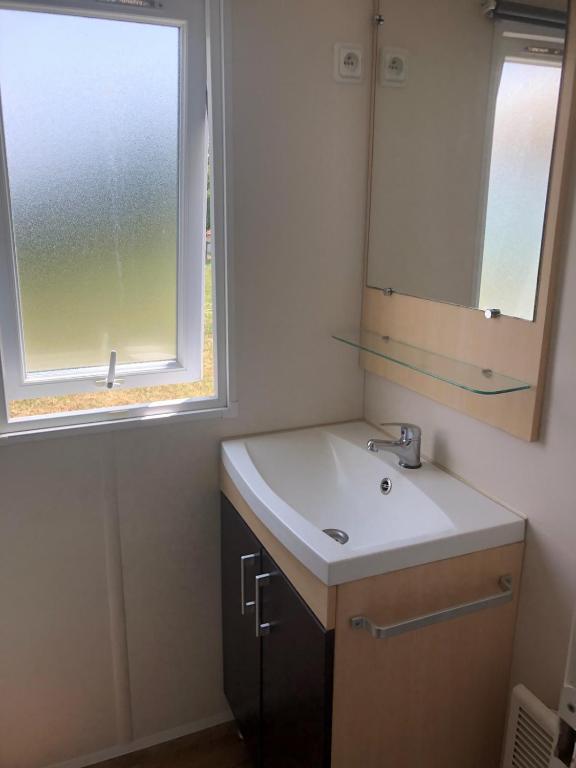 a bathroom with a sink and a mirror and a window at Mobil home in Damiatte