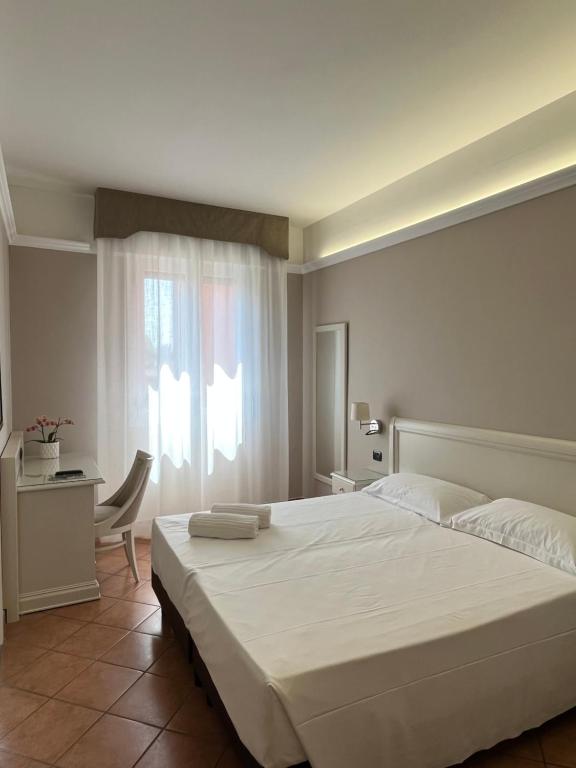 Un dormitorio con una gran cama blanca y una ventana en Hotel Aquila, en Castelfranco Emilia
