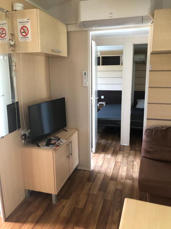 a living room with a television and a room with a bed at Mobil home in Damiatte