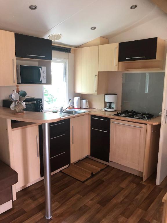 a small kitchen with wooden cabinets and a table at Mobil home in Damiatte
