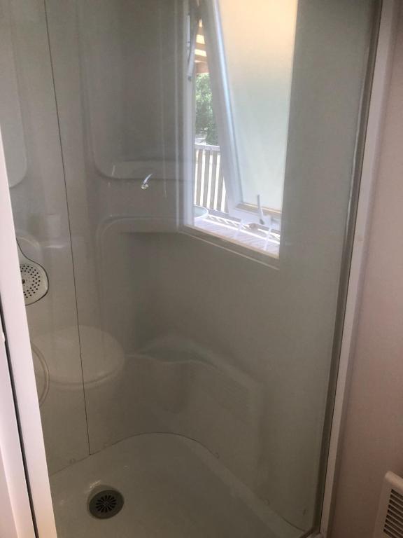 a bathroom with a shower with a toilet and a window at Mobil home in Damiatte