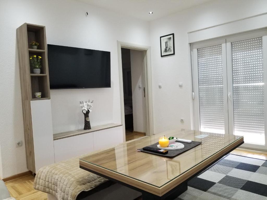 a living room with a table and a flat screen tv at Apartmani Vasković in Trebinje
