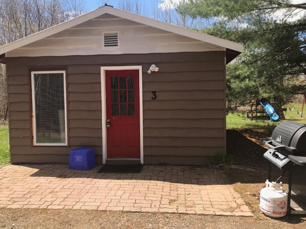 een klein bruin huis met een rode deur bij Hush Lodge and Cottages 