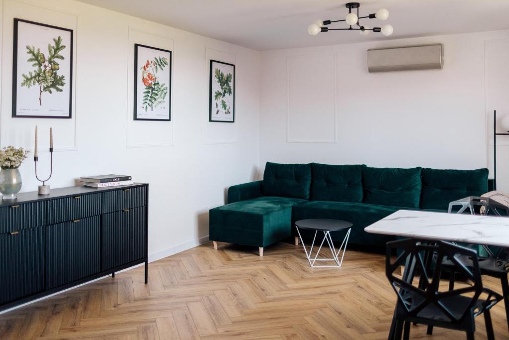 een woonkamer met een groene bank en een tafel bij Apartamenty Koziołek in Srebrna Góra