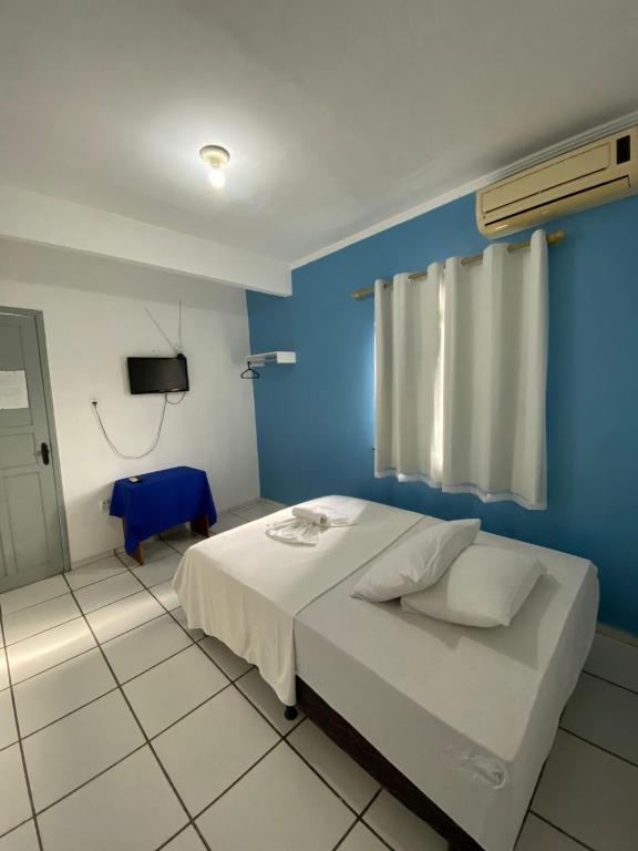 a bedroom with a blue wall and a bed at Pousada o Paraiso in Camamu