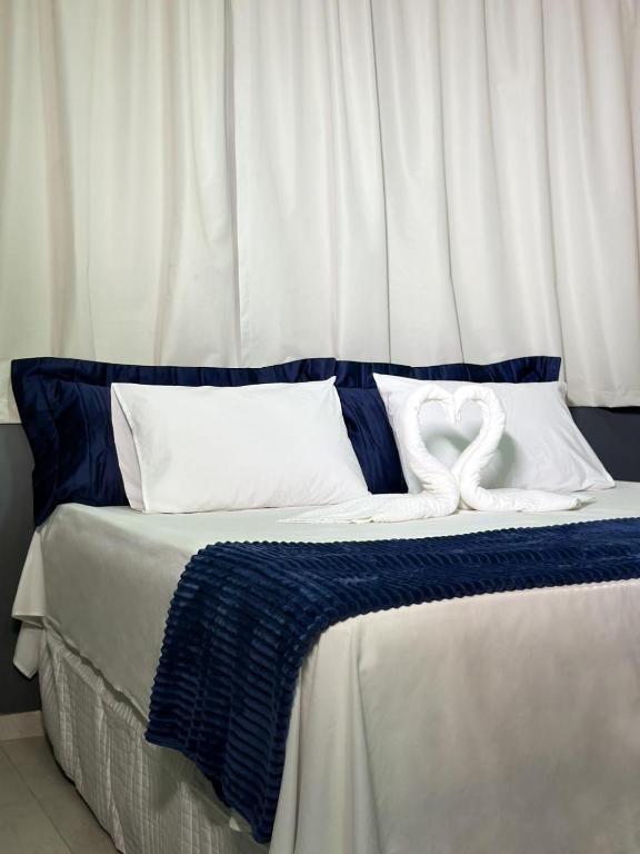 una cama con sábanas azules y blancas y dos almohadas blancas en Haki Hotel, en Patos
