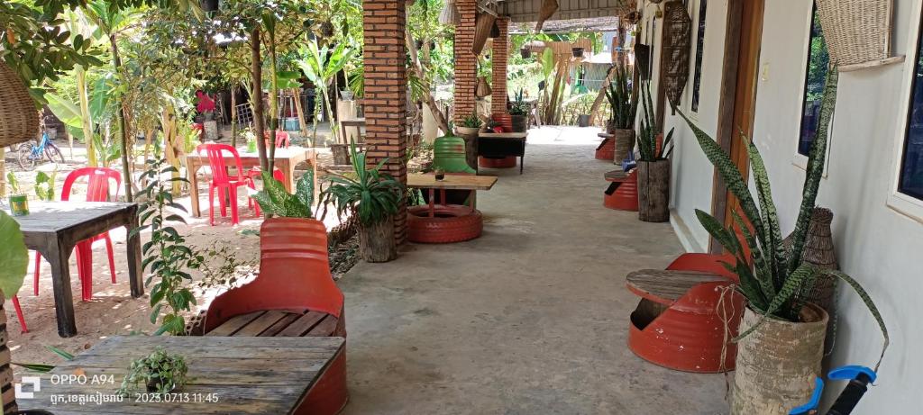 um pátio com mesas, cadeiras e vasos de plantas em Happy Homestay - Local Vibe em Phumĭ Puŏk Chăs