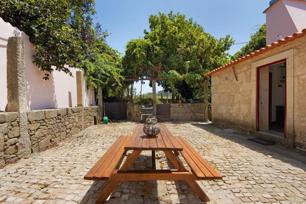 een houten picknicktafel op een stenen binnenplaats bij Casa do Outeiro in Guilhabreu