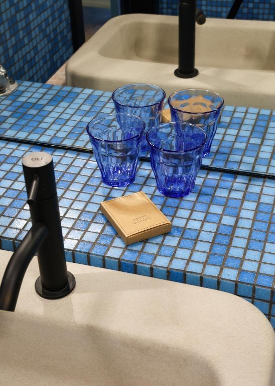 A blue mosaic vanity with four drinking glasses beside a bathtub.